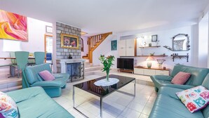 Una sala de estar moderna con sofás color turquesa, una mesa de centro de vidrio, una chimenea y una escalera.