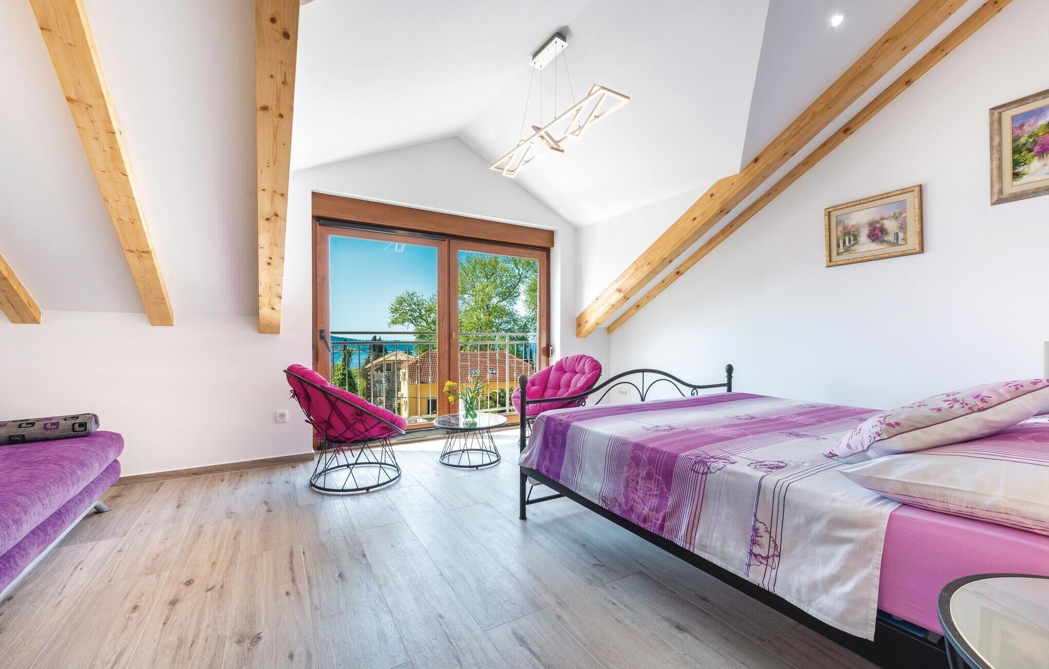 Ein Schlafzimmer mit einem Bett, zwei Stühlen, einem kleinen Tisch und einem Balkon mit Blick.