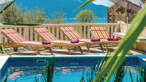 Zona junto a la piscina con sillones de descanso y vistas al mar.