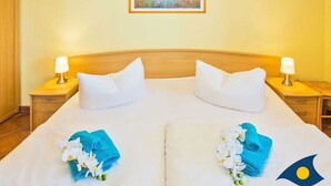 Une chambre d’hôtel avec un grand lit, deux tables de chevet avec des lampes, un tableau au mur et un petit objet décoratif sur le côté droit.