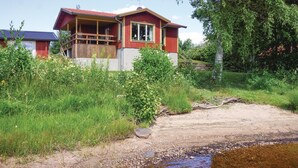 Une maison dotée d’un porche, entourée de verdure et bordée d’un petit ruisseau.
