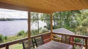 Une terrasse en bois avec une table et des chaises donnant sur un lac.