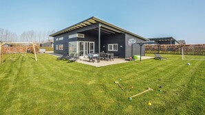 Une maison moderne dotée d’un patio, d’un panier de basketball et d’une balançoire.