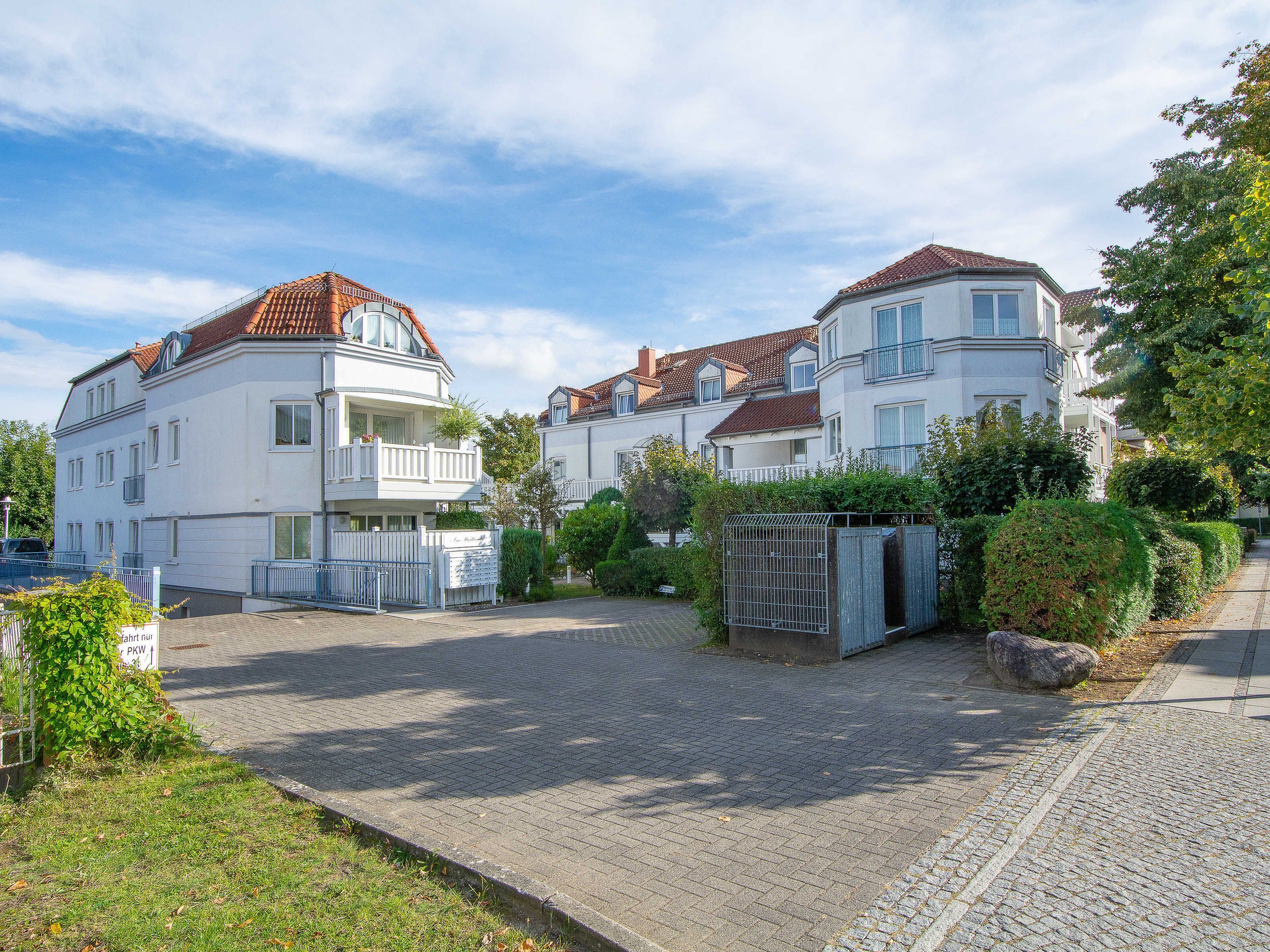 Un quartier résidentiel composé de deux immeubles blancs, chacun doté d’un balcon et d’un toit recouvert de tuiles rouges.