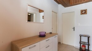 Un couloir avec un meuble en bois, un miroir et une petite table sur laquelle se trouve un vase.
