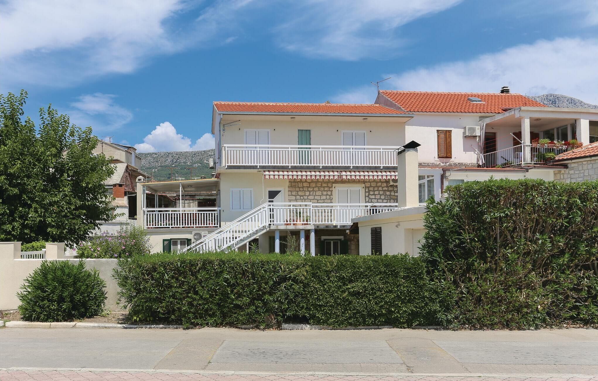 A multi-story building with balconies, a stone facade, and a red-tiled roof.