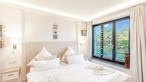 Una habitación de hotel con una cama grande, una ventana que da a zonas verdes y una mesita de noche con una lámpara.