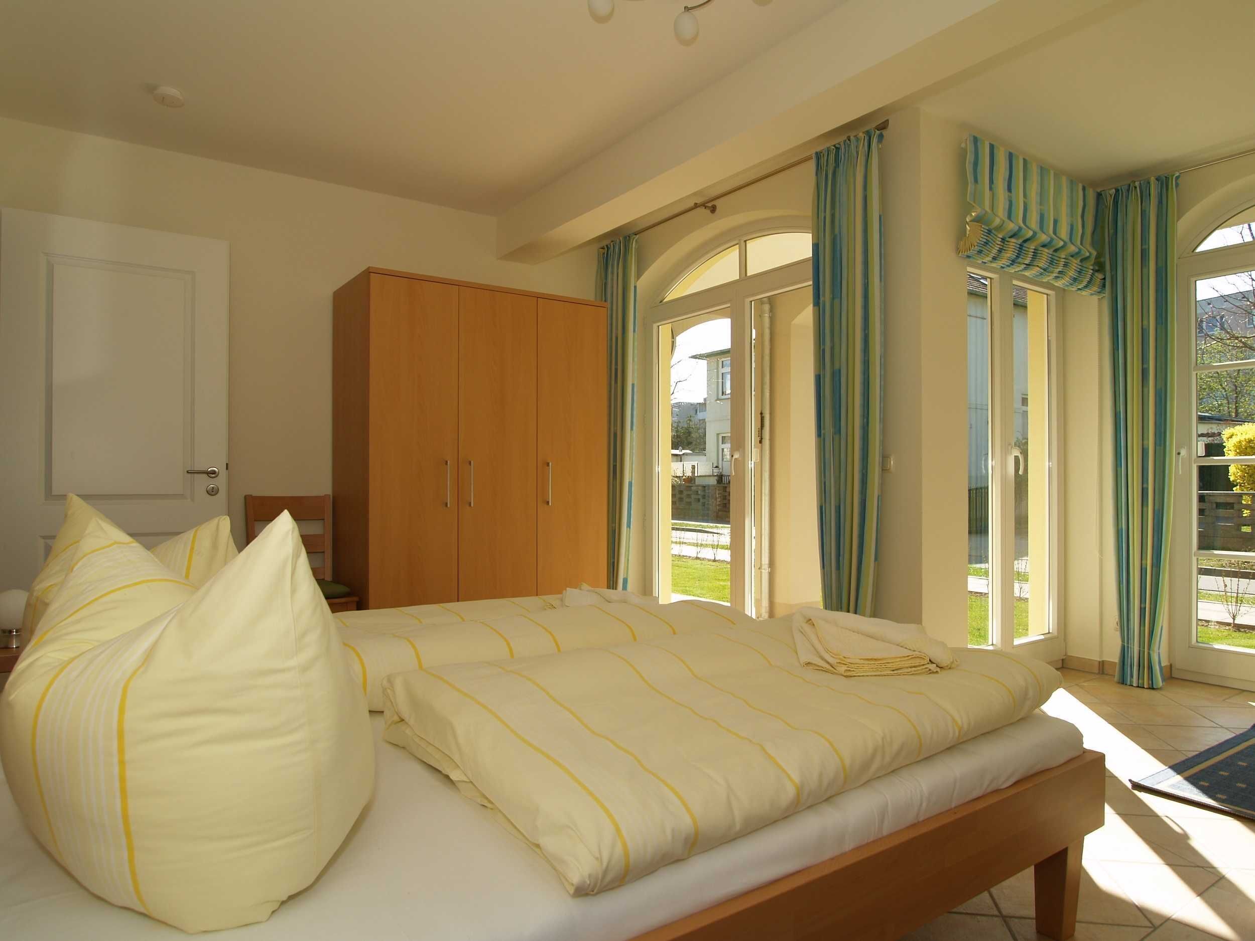 Quarto com cama, guarda-roupa e vista para o exterior através de uma porta de vidro.