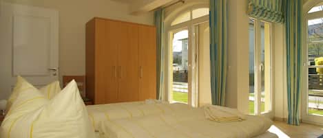 Quarto com cama, guarda-roupa e vista para o exterior através de uma porta de vidro.