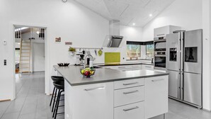 Et moderne køkken med en central ø, rustfrie stålensapparater og en lys, åben indretning.