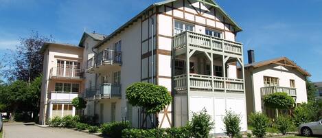 A multi-story building with balconies, a central courtyard, and a paved driveway.