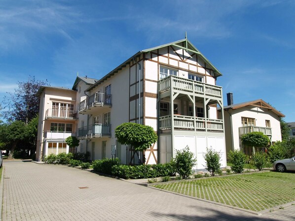 A multi-story building with balconies, a central courtyard, and a paved driveway.