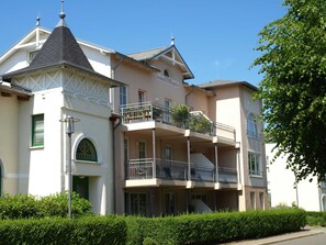 A multi-story building with a balcony on the second floor, a sign reading "Residenzengarten," and a small garden area. - LG-08 - Residenz Lindengarten Whg. LG-08th (Kühlungsborn)