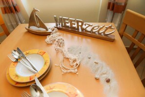 A table set with plates, cutlery, and a decorative sailboat. - (192) 2-room apartment lake view - Apartment house Baltic Sea beach (Kühlungsborn)