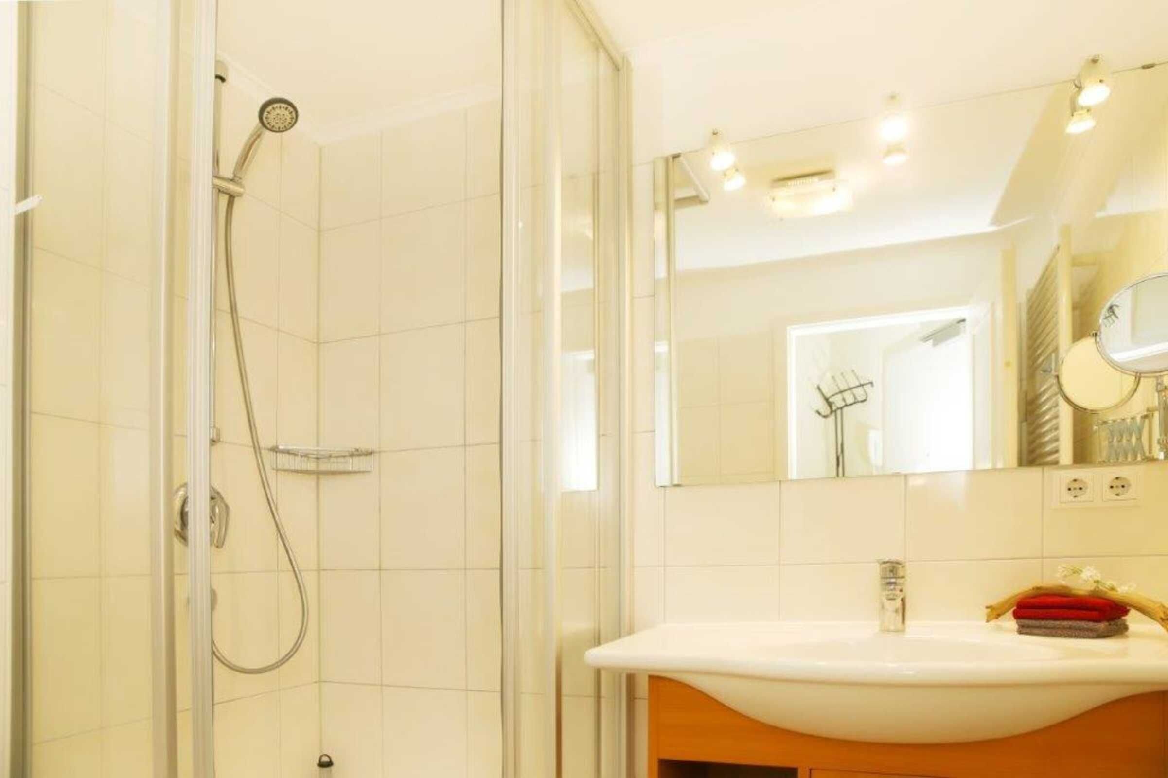 A bathroom with a glass shower enclosure, a white sink with a mirror, and a towel rack.