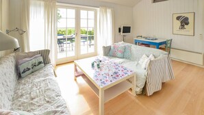 A cozy living room with a sofa, a coffee table, and a TV. There is a window with curtains and a view of greenery outside. - Gorgeous home in Sydals with WiFi (Sydals)