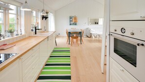 A modern kitchen with white cabinetry, a wooden countertop, a dining area with a table and chairs, and a large oven. - Gorgeous home in Sydals with WiFi (Sydals)