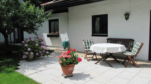 A patio with a table and chairs, a potted plant, and a building with windows.