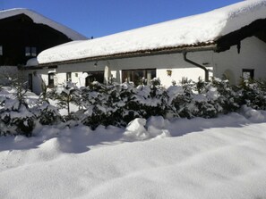 A building with a snow-covered roof and a snow-covered garden.