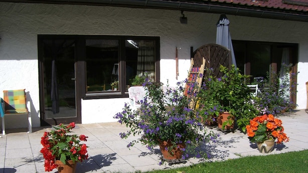 A house with a tiled patio, potted plants, and a chair.