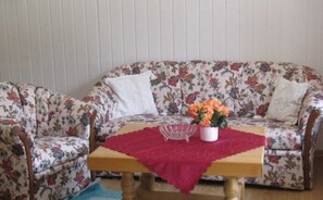 A floral-patterned sofa with a wooden table and a red tablecloth.