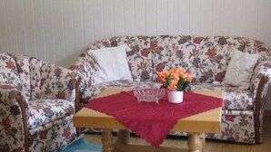 A floral-patterned sofa with a wooden table and a red tablecloth.