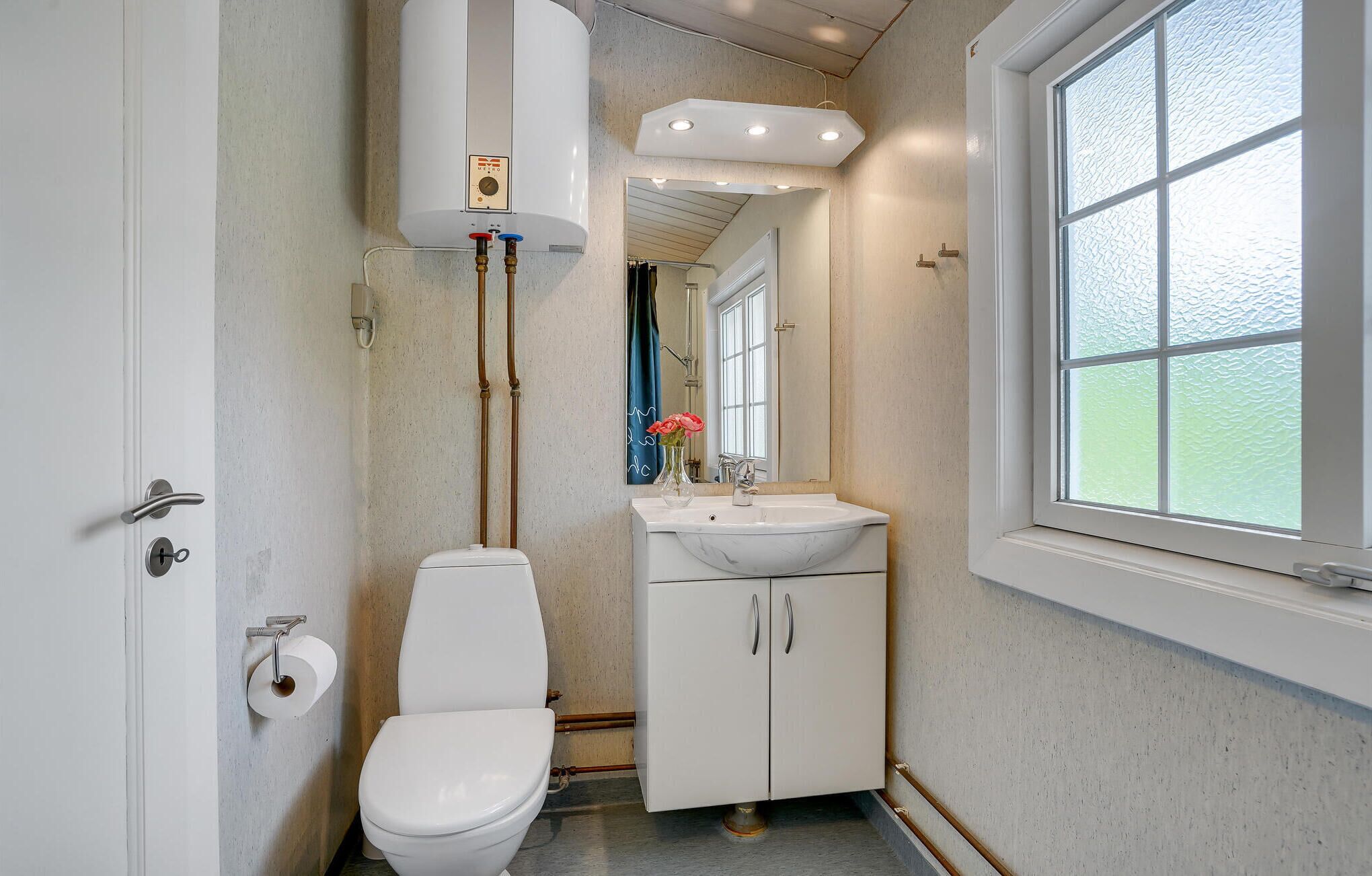 A compact bathroom with a toilet, sink, and window.