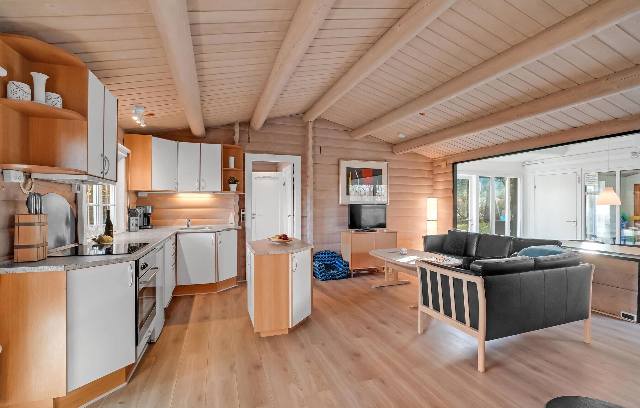 A modern log cabin interior with a kitchen, dining area, and living room.