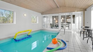 An indoor swimming pool with clear glass walls, a wooden ceiling, and a view of the outside. - Beautiful home in Farsø with kitchen (Farsø)