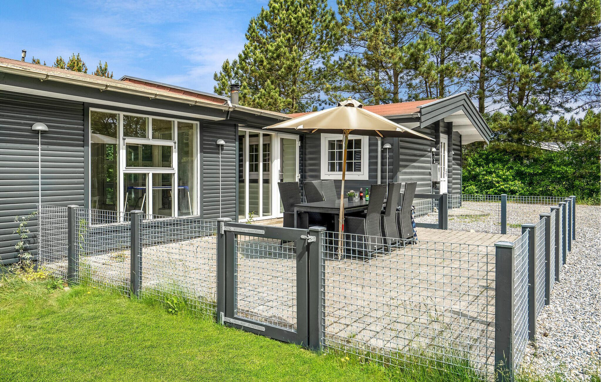 Una cabaña con un patio, una zona de estar techada y un espacio exterior cercado.