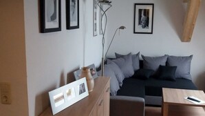A modern bedroom with a bed, bedside table, and a dresser. There are framed pictures on the wall and a floor lamp. - Apartment 3 - Guesthouse Alte Schule (Schwarz)