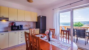 A kitchen with a dining area, a refrigerator, a coffee maker, and a view of the outdoors. - Holiday apartment with balcony (Čižići)