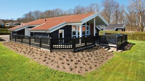 Et hus med skråt tag, en indhegnet have og en velplejet græsplæne.