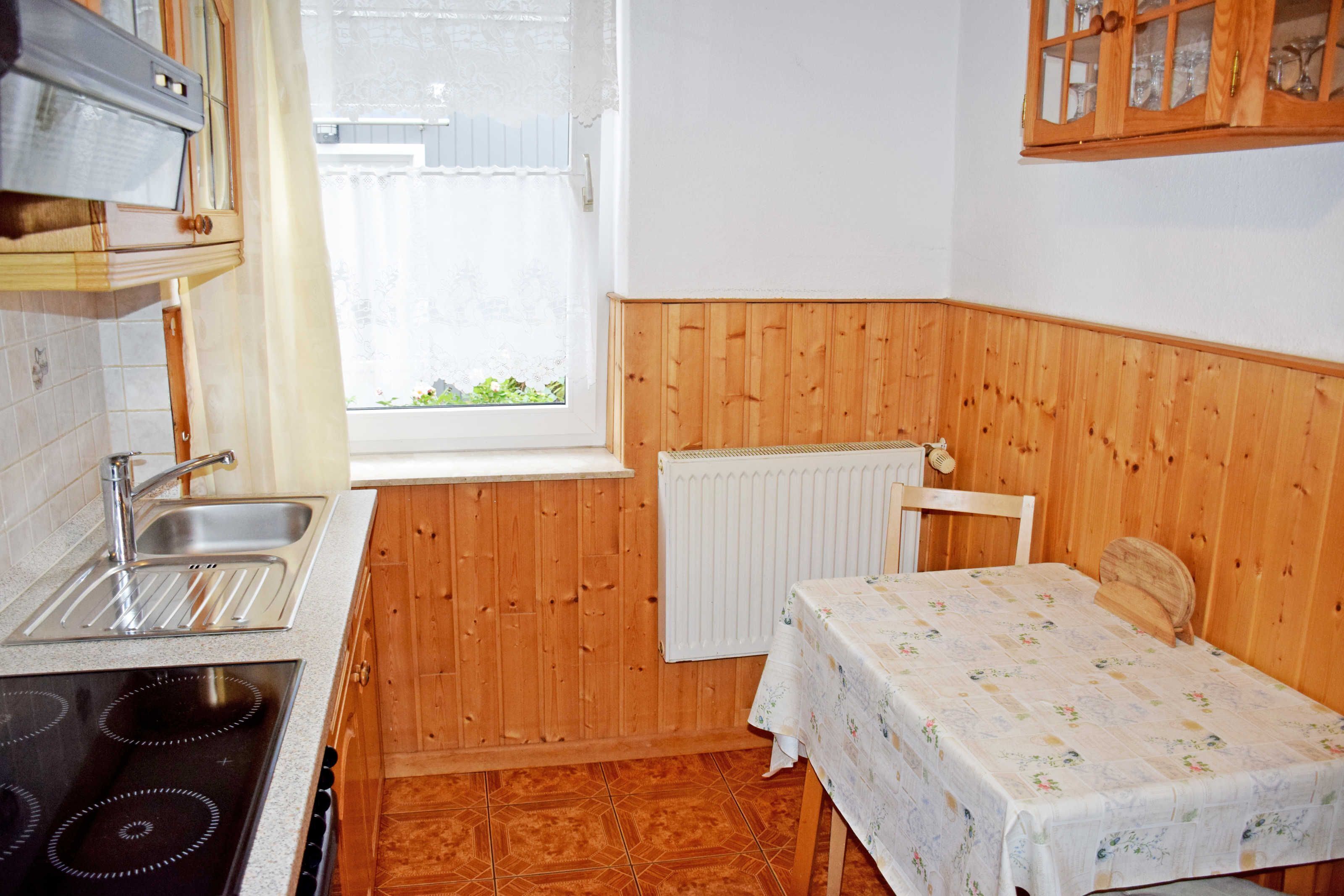 Une cuisine de taille réduite, équipée d’une cuisinière, d’un évier et de panneaux muraux en bois.