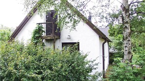 Un edificio bianco con tetto scuro, circondato da un'abbondante vegetazione.