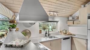 Een moderne keuken met een groot raam, granieten aanrechtbladen en houten keukenkastjes.