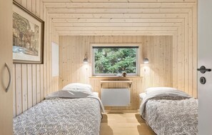 Two single beds with patterned bedding, a large window, and a small table make this compact bedroom a comfortable retreat.