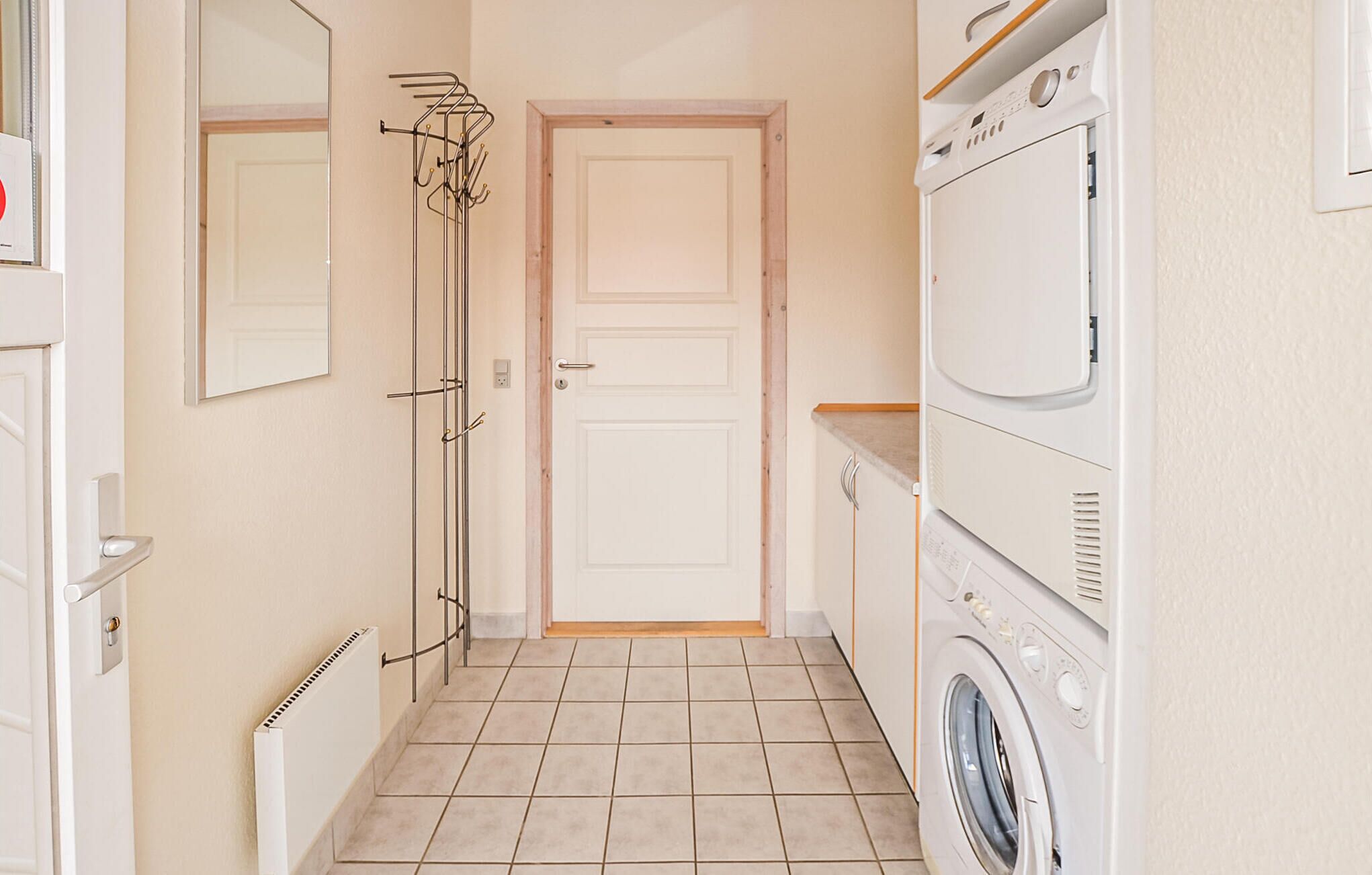 A laundry room with a washing machine, a drying rack, and a door.