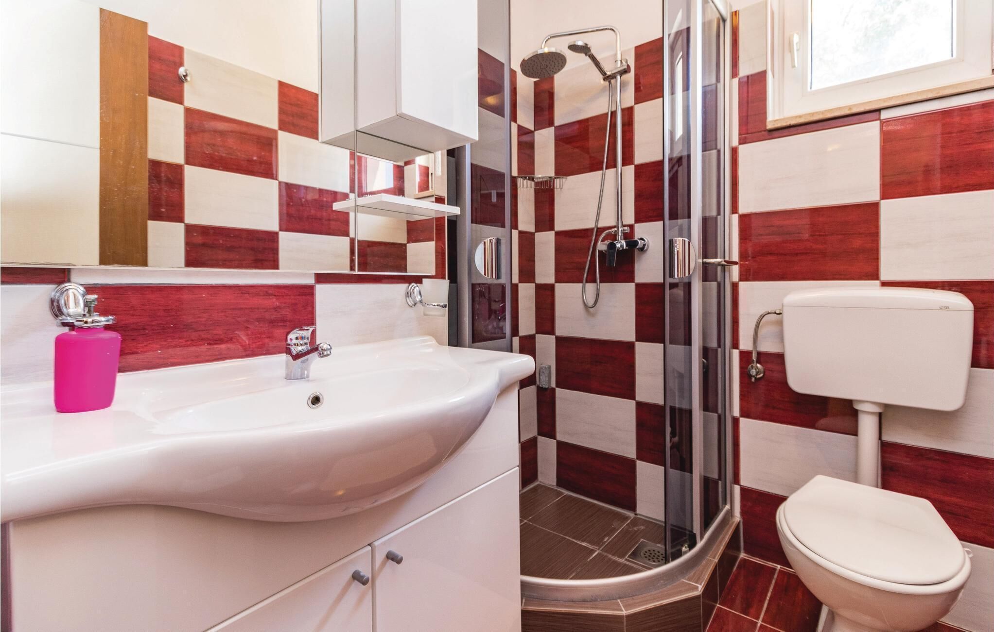 A bathroom with a white sink, a glass shower enclosure, and a toilet.