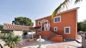Een tweelaags huis met een pannendak, een overdekte veranda en een trap die naar de bovenverdieping leidt.