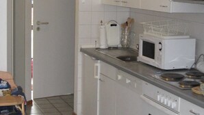Et køkken med hvide skabe, en mikrobølgeovn, ovn og vask.