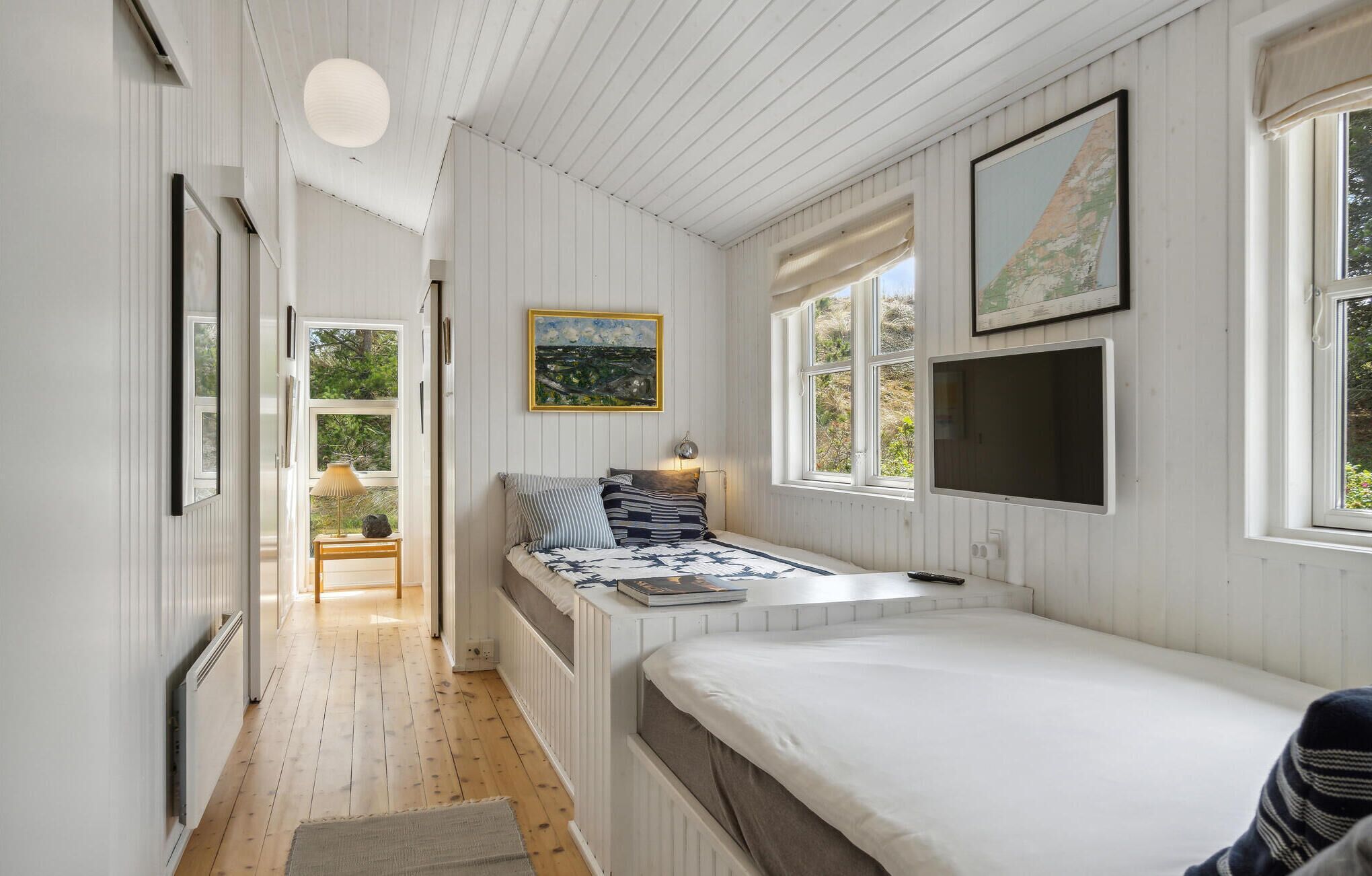 Ein Schlafzimmer mit einem Bett, einem Fernseher, einem Gemälde und einem Fenster.