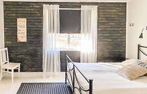 A bedroom with a bed, a chair, a window with curtains, and a sign on the wall. - Amazing home in Bor with WiFi (Bor)
