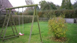 Eine Holzwentilgruppe auf einer grünen Wiese mit einem kleinen Busch und einem Fußball auf dem Boden.