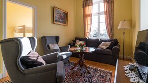 Una sala de estar con un sofá, dos sillones, una mesa de centro y una lámpara de pie.
