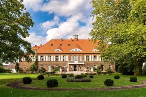 A large brick building with a symmetrical facade, multiple windows, and a central entrance. - Parkblick - Schloss Pütnitz - Canoe special from 4 nights (Jan 06 to April 29) (Ribnitz-Damgarten)