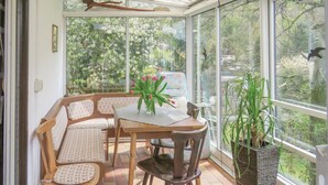 A conservatory with a wooden table and chairs, a vase of flowers, and a potted plant. - Stunning apartment in Hinterweidenthal (Hinterweidenthal)