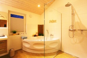 Ein modernes Badezimmer mit einer freistehenden Badewanne, einer Duschkabine und einem Waschtisch mit Spiegel.