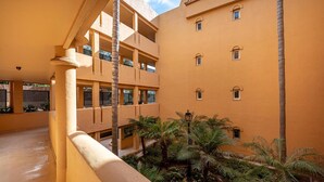 Un patio con piscina, palmeras y un edificio con balcones.