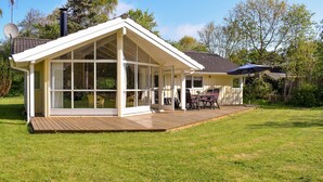 A house with a large glass front, a deck, and a small outdoor seating area. - Stunning home in Gilleleje with kitchen (Gilleleje)